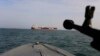 IRAN -- A speedboat of Iran's Revolutionary Guard trains a weapon toward the British-flagged oil tanker Stena Impero, which was seized in the Strait of Hormuz on Friday by the Guard, in the Iranian port of Bandar Abbas, July 21, 2019